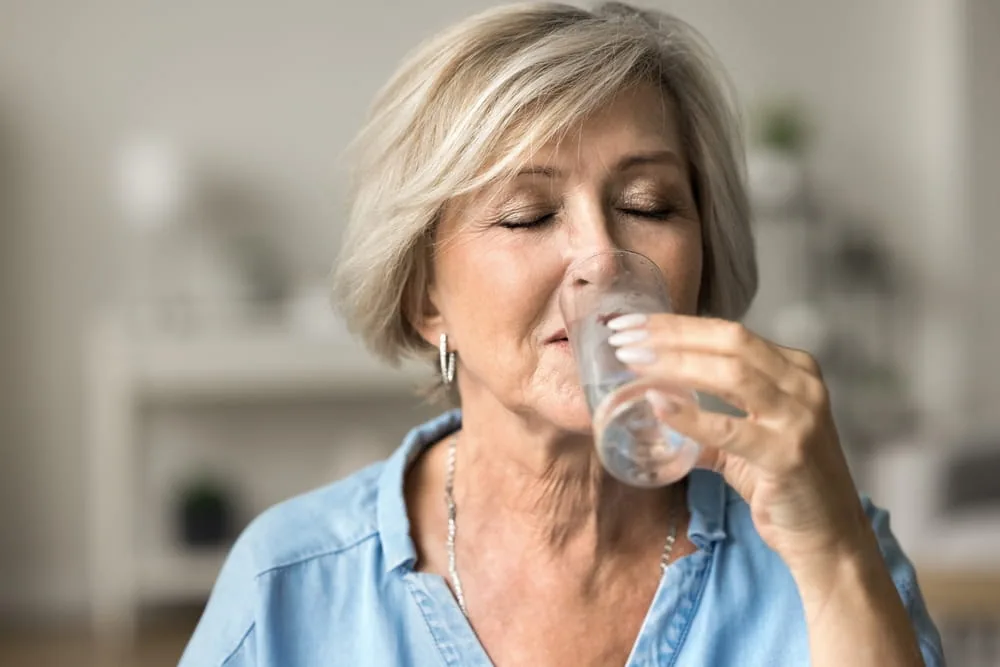 Seniorin trinkt ein Glas Wasser
