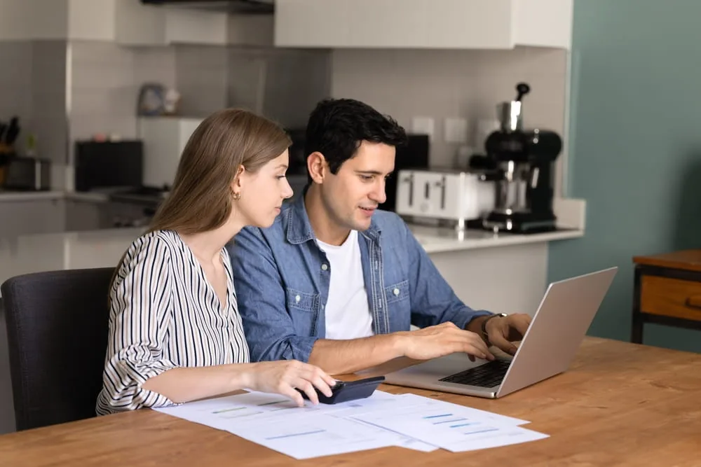 Mann und Frau sitzen am Tisch mit Computer und Taschenrechner